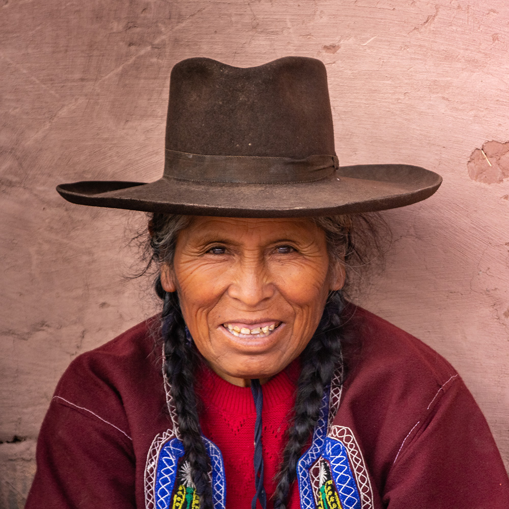 Peru - January, 02 2012: Ethnic woman sitting near stone wall